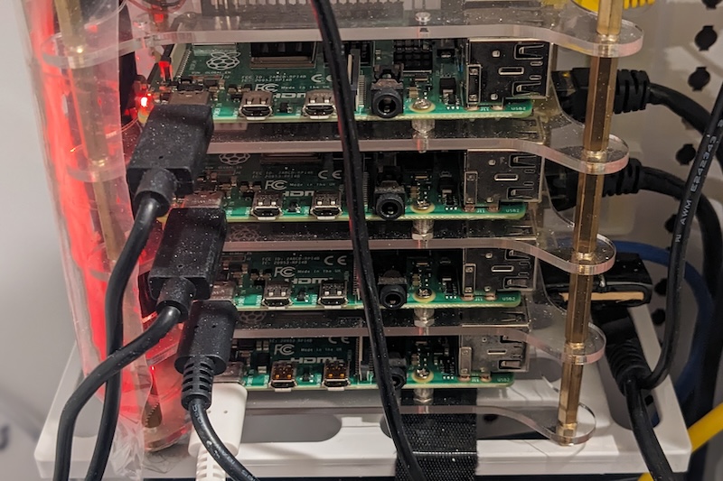 Close-up of the four stacked Raspberry Pi 4 boards showing their HDMI, USB-C power and USB ports, with a red power LED lit on the top board.